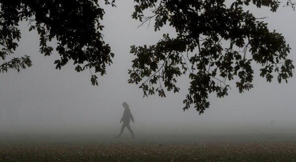 A woman exercises in Hagley Park as fog envelopes Christchurch, New Zealand, Thursday, April 23, 2020. (AP Photo/Mark Baker)