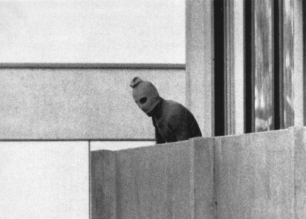 A member of the Arab Commando group which seized members of the Israeli Olympic Team at their quarters appears with a hood over his face on the balcony of the village building where the commandos held members of the Israeli team hostage, at the Munich Olympic Village, on Sept. 5, 1972. A panel of historians set up to review the 1972 attack on the Munich Olympics is starting its three-year mission to reappraise what happened before, during and after the events of five decades ago on Tuesday, the German government said. (AP Photo/Kurt Strumpf, File)