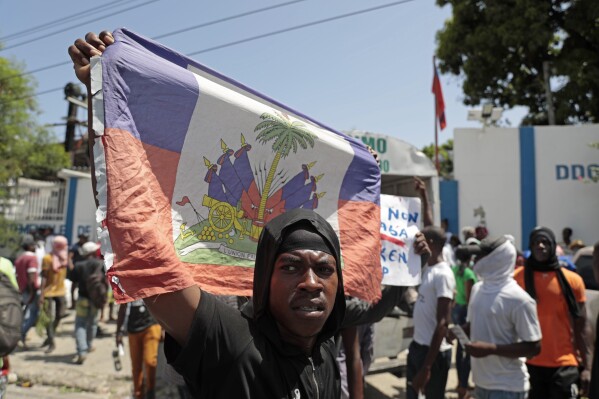 A demonstrator holds up a Haitian flag during a protest against insecurity in Port-au-Prince, Haiti, Monday, Aug. 7, 2023. (AP Photo/Odelyn Joseph)