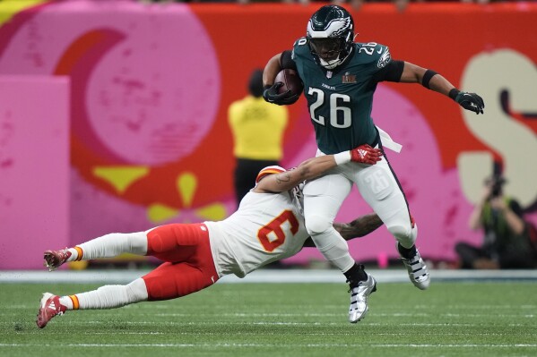 Philadelphia Eagles running back Saquon Barkley (26) tries to elude the tackle of Kansas City Chiefs safety Bryan Cook (6) during the first half of the NFL Super Bowl 59 football game, Sunday, Feb. 9, 2025, in New Orleans. (AP Photo/Frank Franklin II)