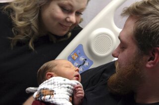 In this Tuesday, Oct. 23, 2018, photo Andrew Goette and his wife, Ashley, look at their baby, Lennon, at United Hospital in Saint Paul, Minn. Andrew awoke from a medically-induced coma just in time for the birth of Lennon after his wife, at 39 weeks pregnant, saved him from cardiac arrest. (Jiwon Choi/Minnesota Public Radio via AP)