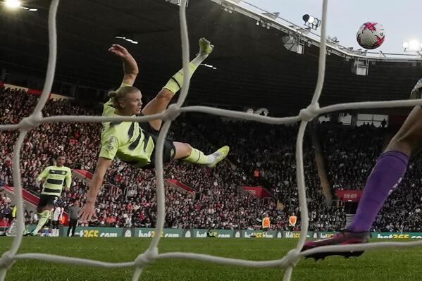 Manchester City's Erling Haaland, centre, scores his side's third goal past Southampton's goalkeeper Gavin Bazunu during the English Premier League soccer match between Southampton and Manchester City at St Mary's Stadium in Southampton, England, Saturday, April 8, 2023. (AP Photo/Frank Augstein)