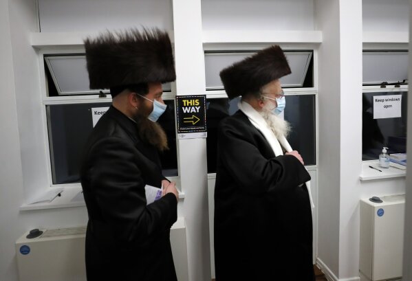 Two men from the Haredi Orthodox Jewish community arrive at an event to encourage vaccine uptake in Britain's Haredi community at the John Scott Vaccination Centre in London, Saturday, Feb. 13, 2021. In hopes of breaking down barriers that sometimes isolate the Orthodox from wider society, community leaders organized the pop-up vaccination event for Saturday night to coincide with the end of Shabbat, the Jewish day of rest. (AP Photo/Frank Augstein)