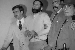 FILE - Law officials escort a handcuffed David Gilbert, second from left, from the Rockland County Court in New City, New York, on Nov. 23, 1981. Gilbert, a former Weather Underground member, described his path from nonviolent 1960s activist to would-be revolutionary during a 4 1/2-hour hearing before the New York state parole board panel that approved his parole in October, 40 years after he served as a getaway driver in the botched Brink's robbery that left three men dead and several others wounded. (AP Photo/David Handschuh, File)
