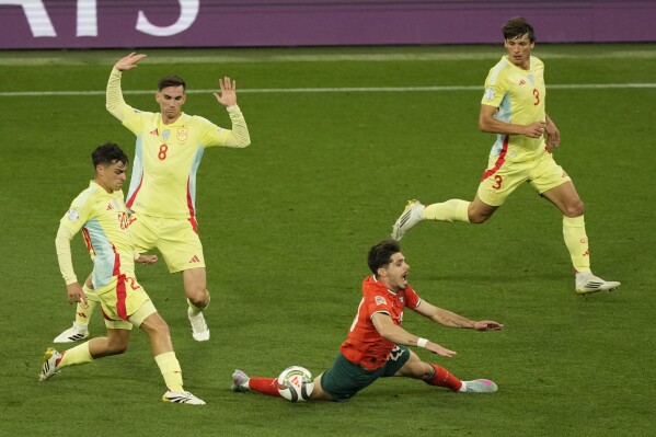 Portugal's Pedro Neto falls challenged by Spain's Pedri during the Nations League final soccer match between Portugal and Spain at the Allianz Arena in Munich, Germany, Sunday, June 8, 2025. (AP Photo/Michael Probst)