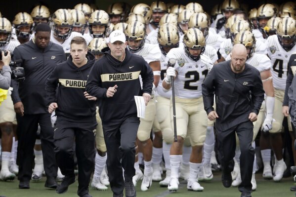 FILE - In this Dec. 28, 2018, file photo, Purdue coach Jeff Brohm, center, leads his team onto the field for the the team's NCAA college football game in the Music City Bowl against Auburn in Nashville, Tenn. Brohm knows he has a young team. "We have a lot to prove." Coming off breakout freshman seasons, Purdue wide receiver Rondale Moore and Nevada running back Toa Taua headline Friday night's non-conference opener on the edge of the Sierra where both third-year coaches are anxious to turn the corner on rebuilding efforts. (AP Photo/Mark Humphrey, File)