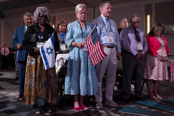 Holding U.S. and Israeli flags, a crowd of largely Evangelical Christians pray during the Christians United For Israel (CUFI) "Night to Honor Israel" during the CUFI Summit 2023, Monday, July 17, 2023, in Arlington, Va., at the Crystal Gateway Marriott. (AP Photo/Jacquelyn Martin)