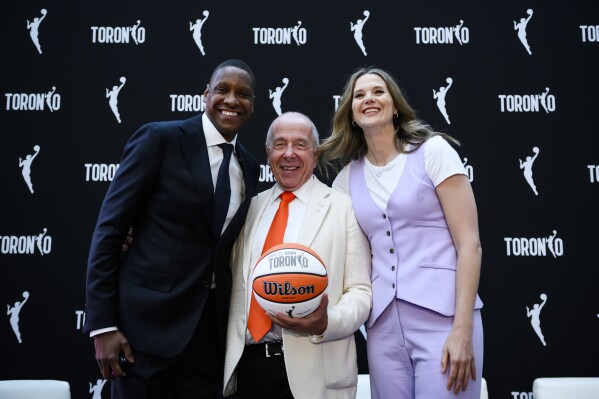 Toronto Raptors president Masai Ujiri, left, Larry Tanenbaum of Kilmer Sports Ventures and WNBA Toronto team president Teresa Resch pose for a photo during a press conference announcing the city's WNBA franchise, in Toronto on Thursday, May 23, 2024. (Christopher Katsarov/The Canadian Press via AP)