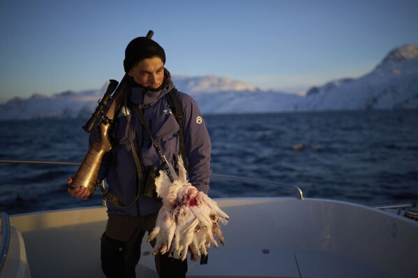 Bilo Chemnitz, 23, holds his rifle after hunting ptarmigan birds near the Nuuk fjord in Greenland, Monday, Feb. 17, 2025. (AP Photo/Emilio Morenatti)