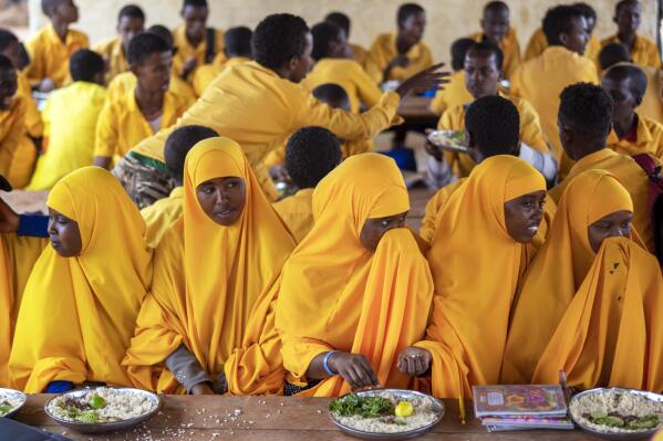 Students eat at a school in Dollow, Somalia, on Monday, Sept. 19, 2022. At midday, dozens of hungry children from the camps try to slip into a local primary school where the World Food Program offers a rare lunch program for students. (AP Photo/Jerome Delay)