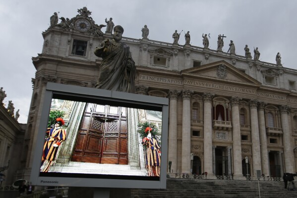 A giant monitor in St. Peter's Square at the Vatican, Tuesday, March 12, 2013 shows the heavy wooden door to the Sistine Chapel being closed and locked, signaling the start of the conclave to elect a new pope to succeed Benedict XVI following his stunning resignation. (AP Photo/Gregorio Borgia, File)