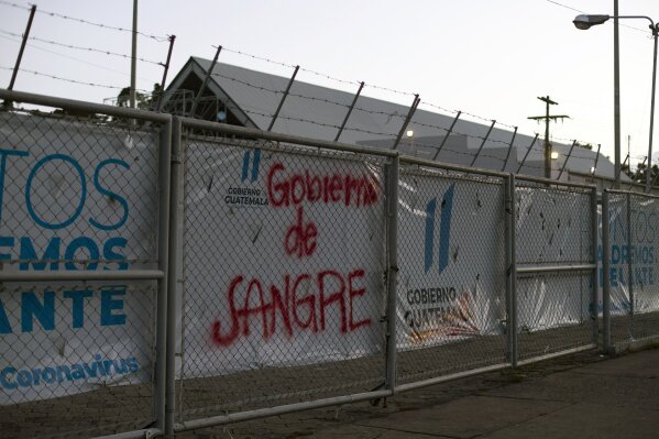 Graffiti that reads in Spanish: "Blood Government," is painted on a fence of a temporary hospital for coronavirus patients in Guatemala City, Saturday, July 11, 2020. Dr. Oscar Hernandez Alonzo, 45, who'd been treating COVID-19 patients since March, died Saturday from complications related to the coronavirus. (AP Photo/Moises Castillo)