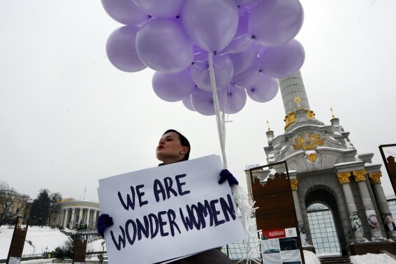 A woman holds balloons and a poster to mark International Women's Day in central Kiev, Ukraine, Thursday, March 8, 2018. (AP Photo/Efrem Lukatsky)