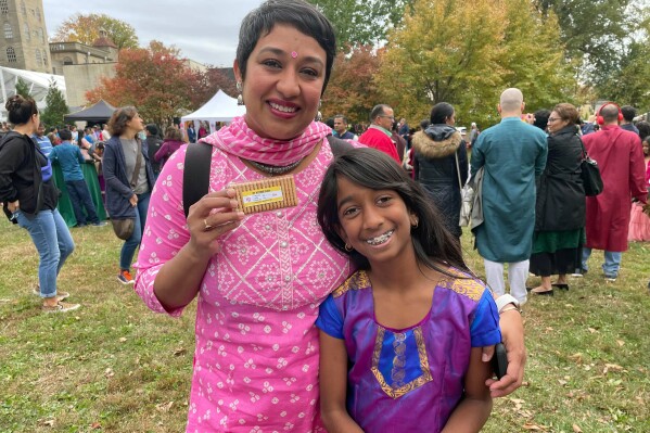 In this image provided by Sarah Shah, the advocacy group Indian American Impact, which runs the fact-checking site Desifacts.org, passes out Parle-G cookies with voting plan stickers at a Diwali even in Doylestown, Pa., on Oct. 23, 2022. Community organizations are gearing up for what they expect will be a worsening onslaught of disinformation targeting voters of color as the 2024 election approaches. (Sarah Shah via AP)