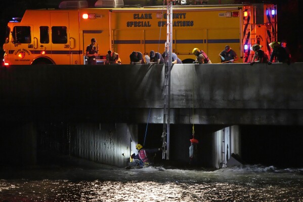 Clark County Fire Department officials searche for a man who was trapped in floodwaters in a flood channel Friday, Sept. 1, 2023, in Las Vegas. (AP Photo/John Locher)