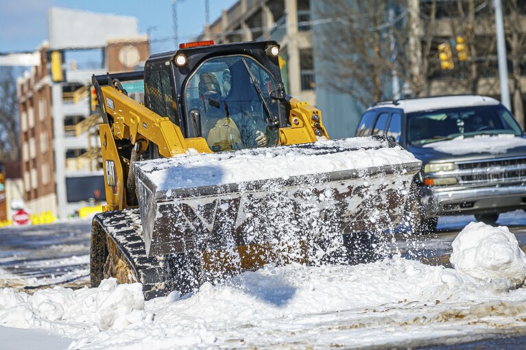 A skid steer with the City of Florence works to clear portions of roadway at Pine and West College Streets Tuesday, Jan. 16, 2024 in downtown Florence, Ala. (Dan Busey/The TimesDaily via AP)