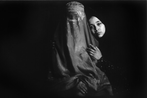 Hakimeh, 55, is embraced by her daughter, Freshta, 16, while posing for a portrait in a carpet factory where they have been working for a year, in Kabul, Afghanistan, Monday, May 29, 2023. Before this, Hakimeh worked in the homes of the wealthy. Freshta had studied until eighth grade when schools closed and helps to earn money and support her family. Her husband is a laborer who works with a cart in the city. (AP Photo/Rodrigo Abd)