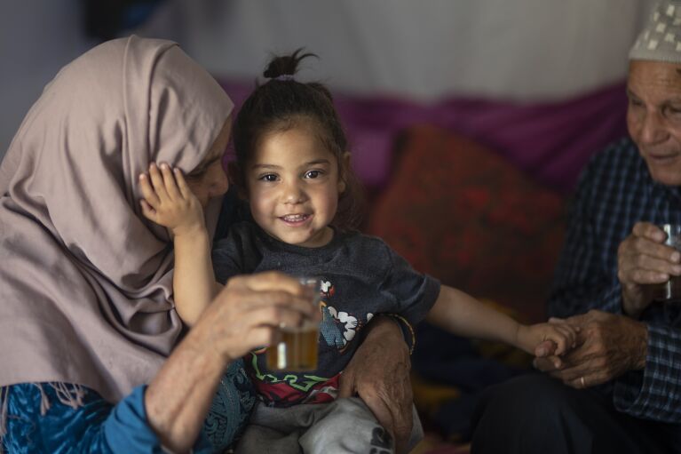 Hocine Azab and his wife Zahrat play with their grand daughter in their tent, after they were displaced by the September earthquake, in Moulay Brahim, outside Marrakech, Morocco, Saturday, Oct. 7, 2023. (AP Photo/Mosa'ab Elshamy)