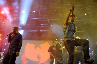 FILE - In this April 21, 2013, file photo, members of the Wu-Tang Clan perform on stage in front of their band logo at the Coachella Valley Music and Arts Festival at the Empire Polo Club in Indio, Calif. China has made a formal complaint to Canada over T-shirts with a similar bat-like logo ordered by a Canadian Embassy staffer in Beijing that allegedly mocked China’s response to the coronavirus outbreak, in an apparent mix-up between the city of Wuhan and the hip-hop group. There are allegations the virus originated in bats and then spread to people in the city of Wuhan in late 2019. (John Shearer/Invision via AP)