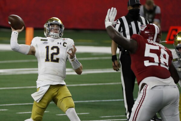 Notre Dame quarterback Ian Book (12) throws a pass under pressure from Alabama defensive lineman Christian Barmore (58) in the first half of the Rose Bowl NCAA college football game in Arlington, Texas, Friday, Jan. 1, 2021. (AP Photo/Roger Steinman)