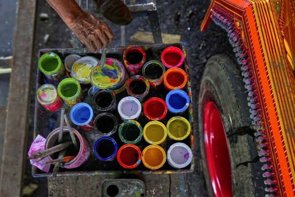 An artisan mixes colors as he paints art on a truck at a yard for workshops in Rawalpindi, Pakistan, on Saturday, April 19, 2025. (AP Photo/Anjum Naveed)