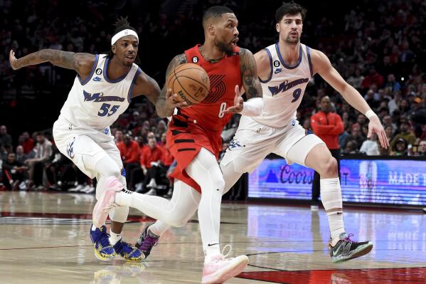 Portland Trail Blazers guard Damian Lillard, center, drives to the basket against Washington Wizards guard Delon Wright, left, and forward Deni Avdija, right, during the first half of an NBA basketball game in Portland, Ore., Tuesday, Feb. 14, 2023. (AP Photo/Steve Dykes)