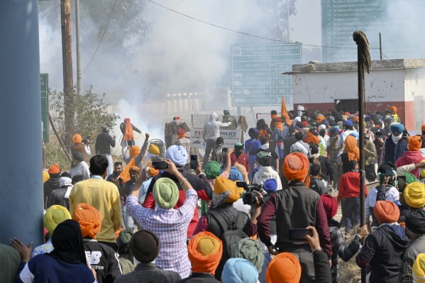 Farmers react after police fired tear gas at protesting farmers near Shambhu border that divides northern Punjab and Haryana states, almost 200 km (125 miles) from New Delhi, India, Wednesday, Feb.14, 2024. Protesting Indian farmers Wednesday clashed with police for a second consecutive day as tens of thousands of them tried to march to the capital New Delhi to demand guaranteed crop prices for their produce. (AP Photo/Rajesh Sachar)