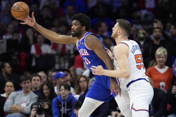 Philadelphia 76ers' Joel Embiid, left, reaches for a pass against New York Knicks' Isaiah Hartenstein during the first half of Game 3 in an NBA basketball first-round playoff series, Thursday, April 25, 2024, in Philadelphia. (AP Photo/Matt Slocum)