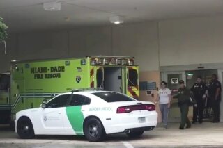 In this image taken from video provided by the Florida Immigrant Coalition, a border patrol agents escorts a woman to a patrol car Sunday, Oct. 13, 2019, at Aventura Hospital in Aventura, Fla. The woman had been detained by border patrol agents, when she fell ill. The agent took her to the hospital emergency room for treatment. The presence of immigration authorities is becoming increasingly common at health care facilities around the country, and hospitals are struggling with where to draw the line to protect patients’ rights amid rising immigration enforcement in the Trump administration. (Florida Immigrant Coalition via AP)