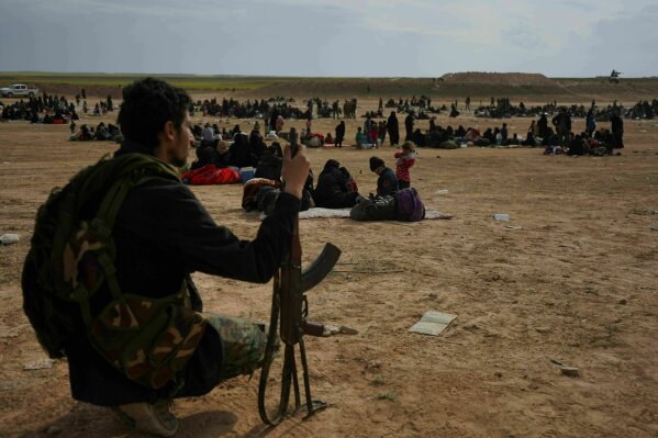
              FILE -- In this March 5, 2019 file photo, a member of U.S.-backed Syrian Democratic Forces (SDF) watches over people who were evacuated out of the last territory held by Islamic State militants, outside Baghouz, Syria. SDF defeated the IS group in March but the Kurdish-led force is now facing protests by local Arab tribesmen in Deir el-Zour province. They are demanding better services, jobs and a bigger role in taking decisions in the predominantly Arab oil-rich and fertile region. (AP Photo/Andrea Rosa, File)
            