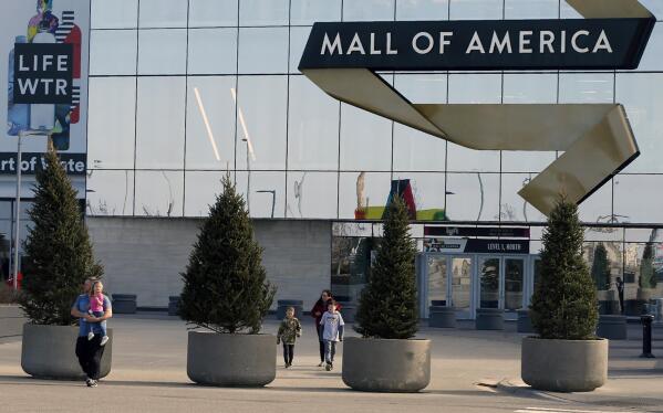FILE - Shoppers, visitors and employees exit the Mall of America on March 17, 2020 as the mall in Bloomington, Minn. The family of a boy who was severely injured when he was thrown off a third-floor balcony at the Mall of America in April 2019 has reached a confidential settlement with the shopping center, which includes making changes to its trespassing policies, the family and mall announced Monday, Dec. 5, 2022. (AP Photo/Jim Mone, File)