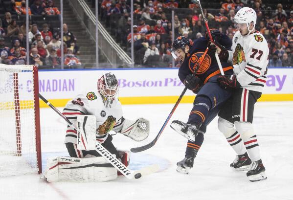 Chicago Blackhawks goalie Kevin Lankinen (32) makes the save as Edmonton Oilers' Zach Hyman (18) and Kirby Dach (77) battle in front during the second period of an NHL hockey game, Saturday, Nov. 20, 2021 in Edmonton, Alberta. (Jason Franson/The Canadian Press via AP)
