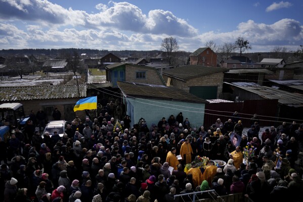 Mourners gather next to the body of Vladyslav Bondarenko 26, during his funeral in Kozyntsi, near Kyiv, Ukraine, Monday, March 6, 2023. Bondarenko, a paratrooper of airmobile brigade, died near Bakhmut on Feb 26, 2023. (AP Photo/Thibault Camus)