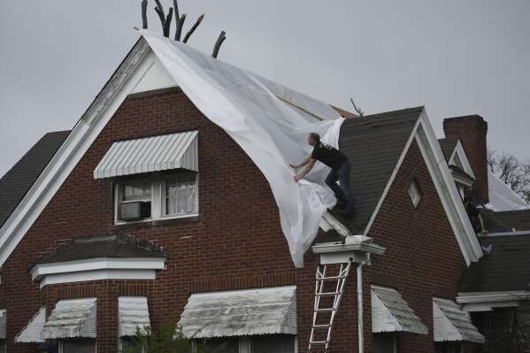 Jeremiah Coyle works to cover a roof in the rain following severe weather in Selmer, Tenn., Thursday, April 3, 2025. (AP Photo/George Walker IV)