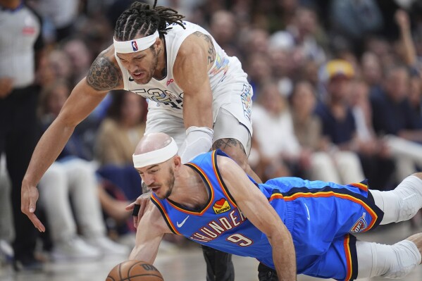 Oklahoma City Thunder guard Alex Caruso, front, dives for a loose ball in front of Denver Nuggets forward Aaron Gordon in the second half of Game 6 in the Western Conference semifinals of the NBA basketball playoffs Thursday, May 15, 2025, in Denver. (AP Photo/David Zalubowski)