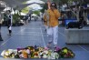A woman brings flowers to an impromptu memorial at Bondi Junction in Sydney, Sunday, April 14, 2024, after several people were stabbed to death at a shopping center Saturday. (AP Photo/Rick Rycroft)