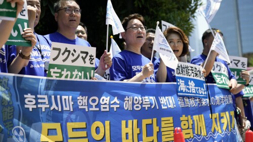 South Korean lawmakers hold placards and a banner against Japanese plans to release treated radioactive water from the damaged Fukushima nuclear power plant, during a rally in front of the Prime Minister's office Monday, July 10, 2023, in Tokyo. The small green placards in Japanese read, 