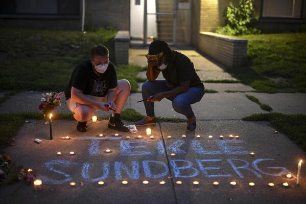 Marcia Howard, activist and George Floyd Square caretaker, right, takes a moment as she lights candles during a vigil for 20-year old Andrew Tekle Sundberg Thursday, July 14, 2022 outside the apartment building where he was killed by Minneapolis Police in Minneapolis. Minneapolis police officers shot and killed Sundberg early Thursday after an overnight standoff that began after he allegedly fired shots inside an apartment building on the city's south side, according to city and state officials. (Aaron Lavinsky/Star Tribune via AP)