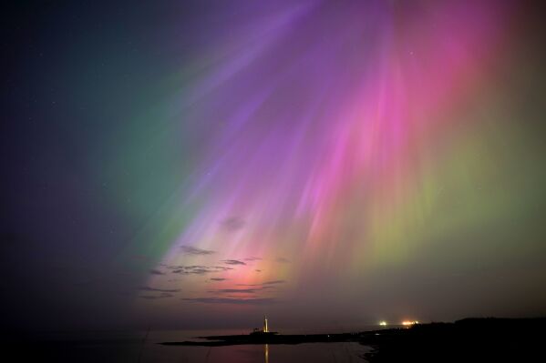 The aurora borealis, also known as the northern lights, glow on the horizon at St. Mary's Lighthouse in Whitley Bay on the North East coast, England, Friday, May 10, 2024. (Owen Humphreys/PA via AP)
