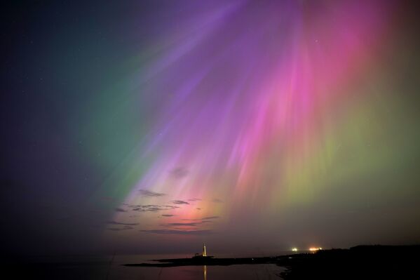 La aurora boreal, también conocida como aurora boreal, brilla en el horizonte en el faro de St. Mary en Whitley Bay, en la costa noreste, Inglaterra, el viernes 10 de mayo de 2024. (Owen Humphreys/PA vía AP)