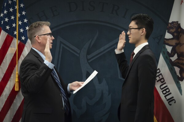 In this photo provided by the Tulare County District Attorney's Office, Peter Park, right, is sworn in by District Attorney Tim Ward in Visalia, Calif., Tuesday, Dec. 5, 2023. A county prosecutor's office says one of its law clerks passed the State Bar of California exam at age 17. The Tulare County District Attorney's Office said that, according to research, Peter Park is the youngest person to pass the exam. (Tulare County District Attorney's Office via AP)