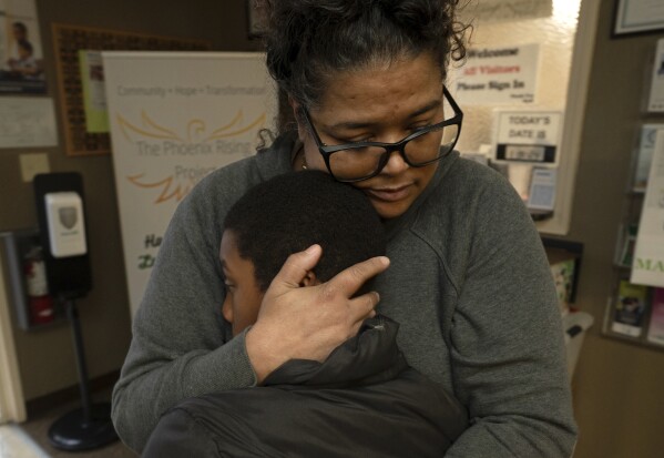 Tiffany McCarter, executive director of the African American Family and Cultural Center, hugs Josiah Banks before he leaves the center for the day in Oroville, Calif., Feb. 8, 2024. A measure aimed at transforming how California spends money on mental health will go before voters in March as the state continues to grapple an unabated homelessness crisis. McCarter fears the 14-year-old facility with a mission of breaking the cycle of trauma in the Black community, might have to close if it loses mental health funding from the Butte County.(AP Photo/Rich Pedroncelli)