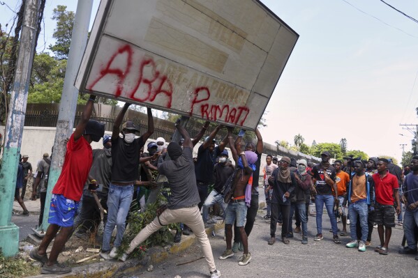 Protesters try to pull down a sign during a protest against insecurity in Port-au-Prince, Haiti, Wednesday, April 2, 2025. (AP Photo/Odelyn Joseph)