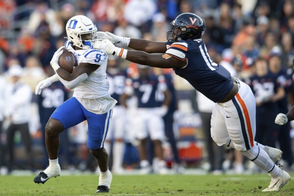 Virginia defensive tackle Michael Diatta, right, is called for face masking as he tries to bring down Duke running back Jaquez Moore (9) during the first half of an NCAA college football game Saturday, Nov. 18, 2023, in Charlottesville, Va. (AP Photo/Mike Caudill)