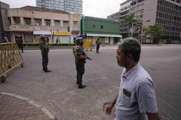 Sri Lankan army soldiers guard a check point outside prime minister's residence a day after clashes between government supporters and anti-government protesters in Colombo, Sri Lanka, Tuesday, May 10, 2022. Defying a nationwide curfew in Sri Lanka, several hundred protesters continued to chant slogans against the government Tuesday, a day after violent clashes saw the resignation of the prime minister who is blamed, along with his brother, the president, for leading the country into its worst economic crisis in decades. (AP Photo/Eranga Jayawardena)