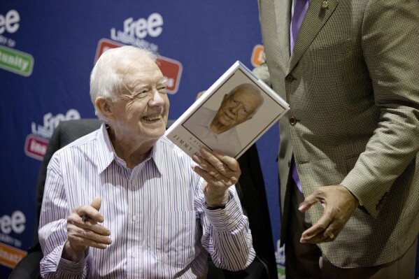 Former President Jimmy Carter hands a copy of his new book, 