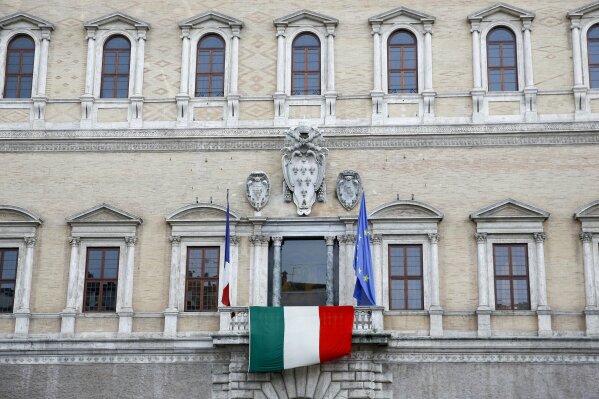 In this photo taken March 27, 2020, the Italian flag hangs from the balcony of the French Embassy in Rome. From tiny San Marino wedged next to two of Italy's hardest-hit provinces in the coronavirus outbreak to more economically powerful nations like Italy, countries are running up against export bans and seizures in the scramble for vital medical supplies. The new coronavirus causes mild or moderate symptoms for most people, but for some, especially older adults and people with existing health problems, it can cause more severe illness or death. (AP Photo/Alessandra Tarantino)