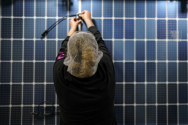 File - An employee works on a solar panel inside the Hanwha Qcells Solar plant, Oct. 16, 2023, in Dalton, Ga. U.S. manufacturers have added 56,000 jobs in the last three months. (AP Photo/Mike Stewart, File)