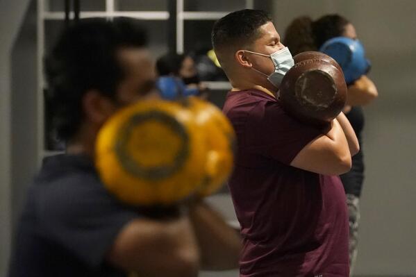FILE - In this Nov. 24, 2020, file photo, Juan Avellan, center, and others wear masks while working out in an indoor class at a Hit Fit SF gym amid the coronavirus outbreak in San Francisco. Health officials in San Francisco and six other Bay Area counties announced Monday, Aug. 2, 2021 that they are reinstating a mask mandate for all indoor setting as COVID-19 infections surge because of the highly contagious delta variant. (AP Photo/Jeff Chiu, File)