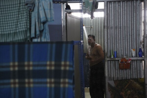 A Bangladeshi migrant worker takes a shower at his dormitory in Klang, Malaysia, Friday, Jan. 24, 2025. (AP Photo/Azneal Ishak).